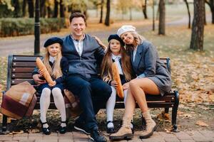 A large family is sitting on a bench in an autumn park. Happy people in the autumn park photo