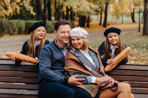 A large family is sitting on a bench in an autumn park. Happy people in the autumn park photo