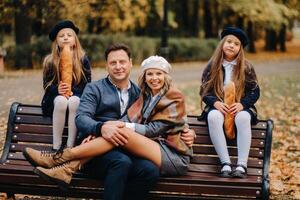 A large family is sitting on a bench in an autumn park. Happy people in the autumn park photo