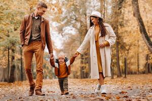 Father and mother with son walking in the autumn Park. A family walks in the Golden autumn in a nature Park. photo