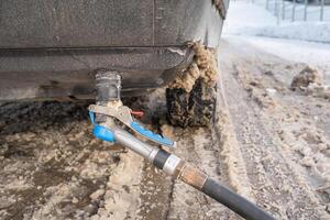 Filling the car from the bottom of the bumper with gas in the winter at the gas station photo