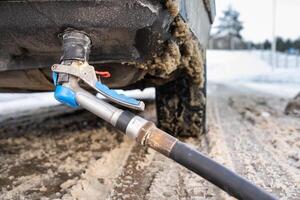 Filling the car from the bottom of the bumper with gas in the winter at the gas station photo