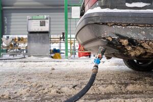 Filling the car from the bottom of the bumper with gas in the winter at the gas station photo