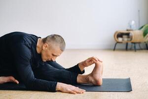 An athletically built man does yoga in the gym on a mat photo