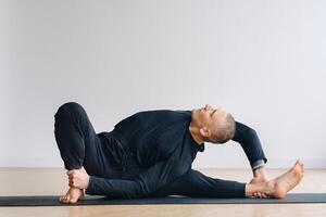 An athletically built man does yoga in the gym on a mat photo
