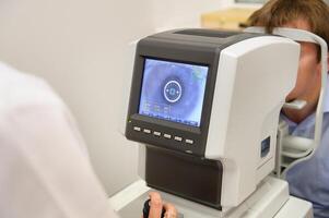 the optometrist controls the oculist display with the scanned eyes of the man, diagnostic ophthalmological equipment photo
