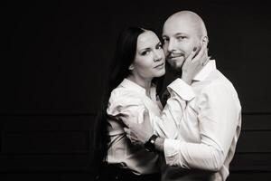 A man and a woman in white shirts on a black background.A couple in love in the studio interior.Black and white photo