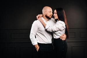 A man and a woman in white shirts on a black background.A couple in love in the studio interior photo