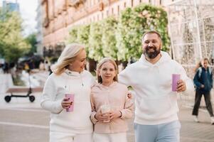 A happy family in white clothes walks in the city and drinks a drink photo