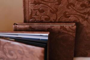 Composition of photo books in natural brown leather of different sizes. Fragment of a photobook binding
