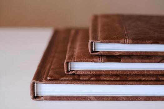 Composition of photo books in natural brown leather of different sizes. Fragment of a photobook binding