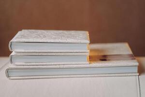 Composition of photo books in natural white leather of different sizes. Fragment of a photobook binding.