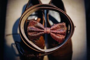 a red bow tie sits on a shelf with a belt and boots photo