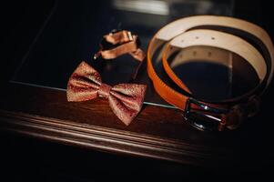 a red bow tie sits on a shelf with a belt photo