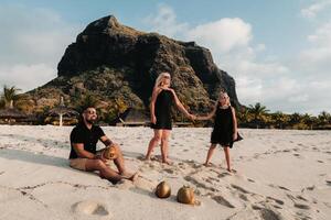a stylish family in black clothes with coconuts in their hands on the beach of the island of Mauritius.Beautiful family on the island of Mauritius in the Indian ocean photo