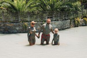 A happy family of three takes mud baths at a resort in Turkey.Family Wellness in therapeutic mud.Turkey photo