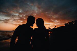 Romantic couple on the beach in a colorful sunset in the background.A guy and a girl at sunset on the island of Tenerife photo