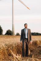 retrato de un empresario en un gris traje en un trigo campo en contra el antecedentes de un molino y el noche cielo foto