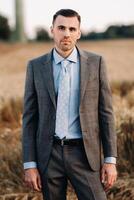 Portrait of a businessman in a gray suit in a wheat field.A man in nature in a jacket and tie photo