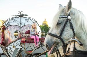 a child sits in the driver's seat in an old carriage on Palace Square in St. Petersburg photo