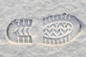 Close-up of a shoe print in the snow, top view of a boot footprint photo