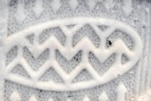 Close-up of a shoe print in the snow, top view of a boot footprint photo