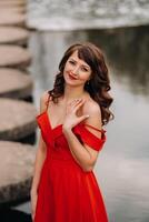 girl in a long red dress near the lake in the Park at sunset. photo