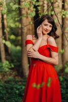 Spring Portrait of a laughing girl in a long red dress with long hair walking in the Park in the woods photo