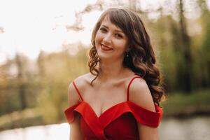 Spring Portrait of a laughing girl in a long red dress with long hair walking in the Park in the woods photo