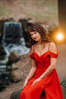 Spring Portrait of a laughing girl in a long red dress with long hair walking in the Park in the woods photo
