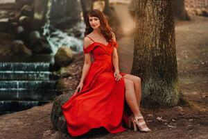 Spring Portrait of a laughing girl in a long red dress with long hair walking in the Park in the woods photo