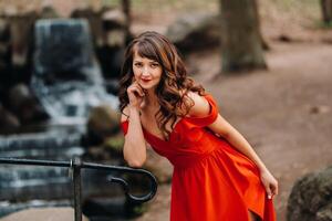 Spring Portrait of a laughing girl in a long red dress with long hair walking in the Park in the woods photo
