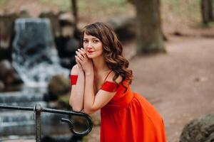 Spring Portrait of a laughing girl in a long red dress with long hair walking in the Park in the woods photo