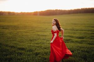 a beautiful girl in spring in a red dress is walking in a field at sunset. Taken from the air by a quadrocopter photo