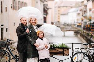 Beautiful family with umbrellas in rainy weather in Annecy. France.Family walk in the rain photo