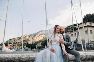 Italy, Lake Garda. A beautiful couple on the shores of lake Garda in Italy at the foot of the Alps.A man and a woman sit on a pier in Italy photo