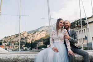 Italy, Lake Garda. A beautiful couple on the shores of lake Garda in Italy at the foot of the Alps.A man and a woman sit on a pier in Italy photo
