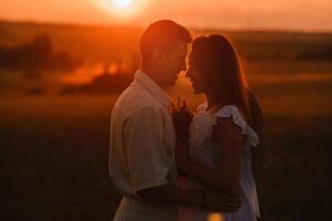 A couple in love in white clothes in a field at a red sunset photo