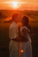 A couple in love in white clothes in a field at a red sunset photo