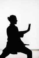 Silhouette of a person practicing qigong energy exercises on a light background photo