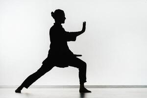 Silhouette of a person practicing qigong energy exercises on a light background photo