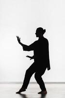 Silhouette of a person practicing qigong energy exercises on a light background photo