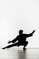 Silhouette of a person practicing qigong energy exercises on a light background photo