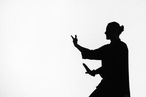 Silhouette of a person practicing qigong energy exercises on a light background photo