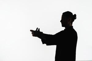 Silhouette of a person practicing qigong energy exercises on a light background photo