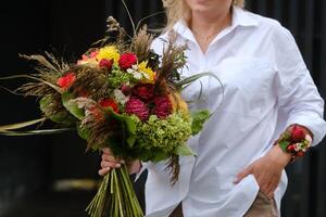 A large bouquet of mixed flowers in the hands of a woman. The work of a florist in a flower shop photo