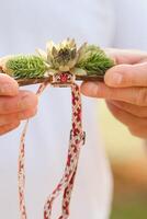 Close-up of hands holding a bow tie with decorative flowers on it photo