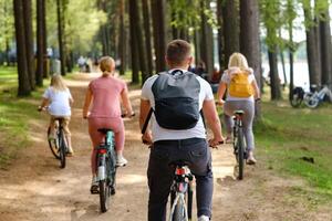 A group of cyclists with backpacks ride bicycles on a forest road enjoying nature photo