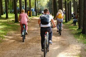 A group of cyclists with backpacks ride bicycles on a forest road enjoying nature photo