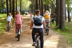 A group of cyclists with backpacks ride bicycles on a forest road enjoying nature photo